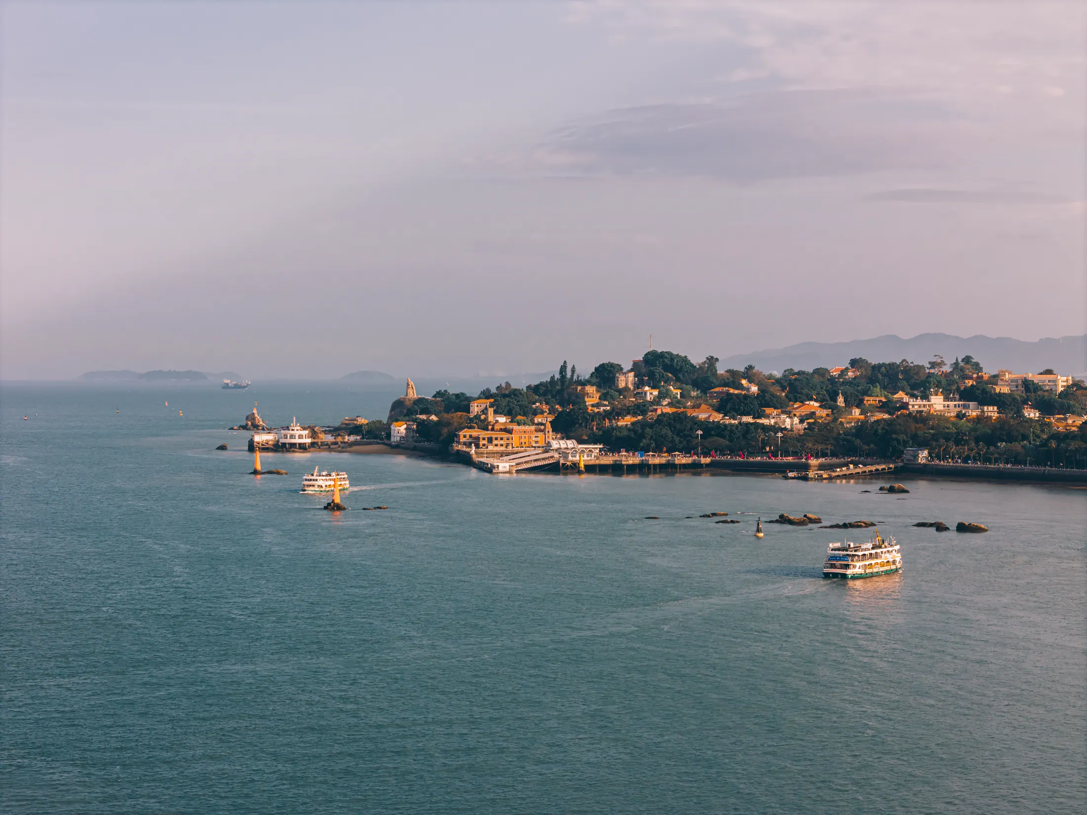 The coastline and islands of Xiamen seen across calm water.