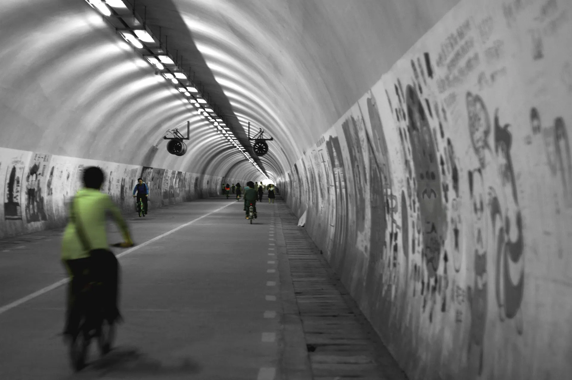 Cyclists passing through a monochrome tunnel in Xiamen.