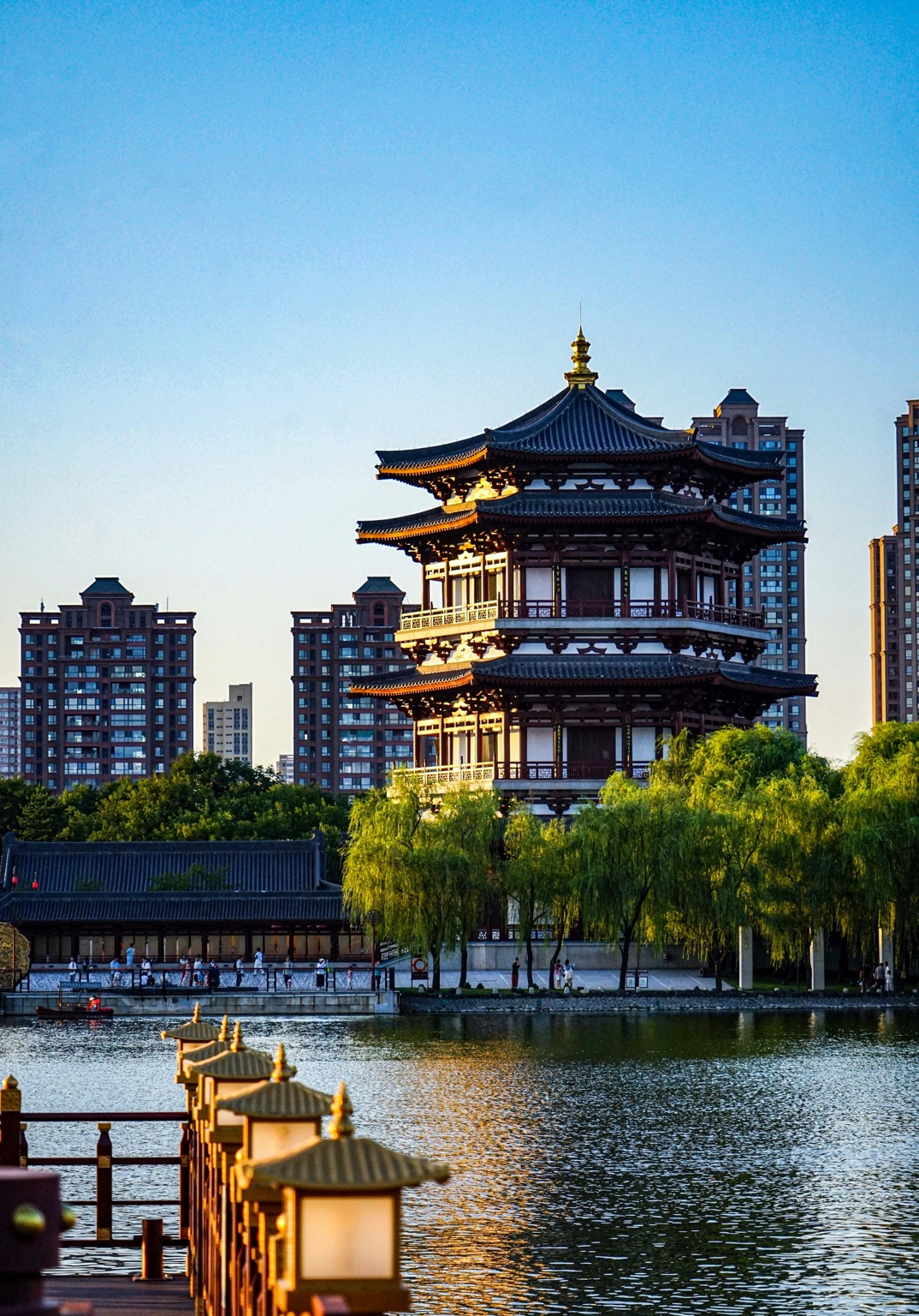 A Tang-style pavilion beside a lake and modern residential skyline